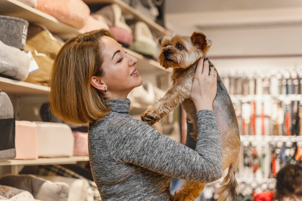 Foto de uma mulher segurando um cachorro yorkshire em um pet shop
