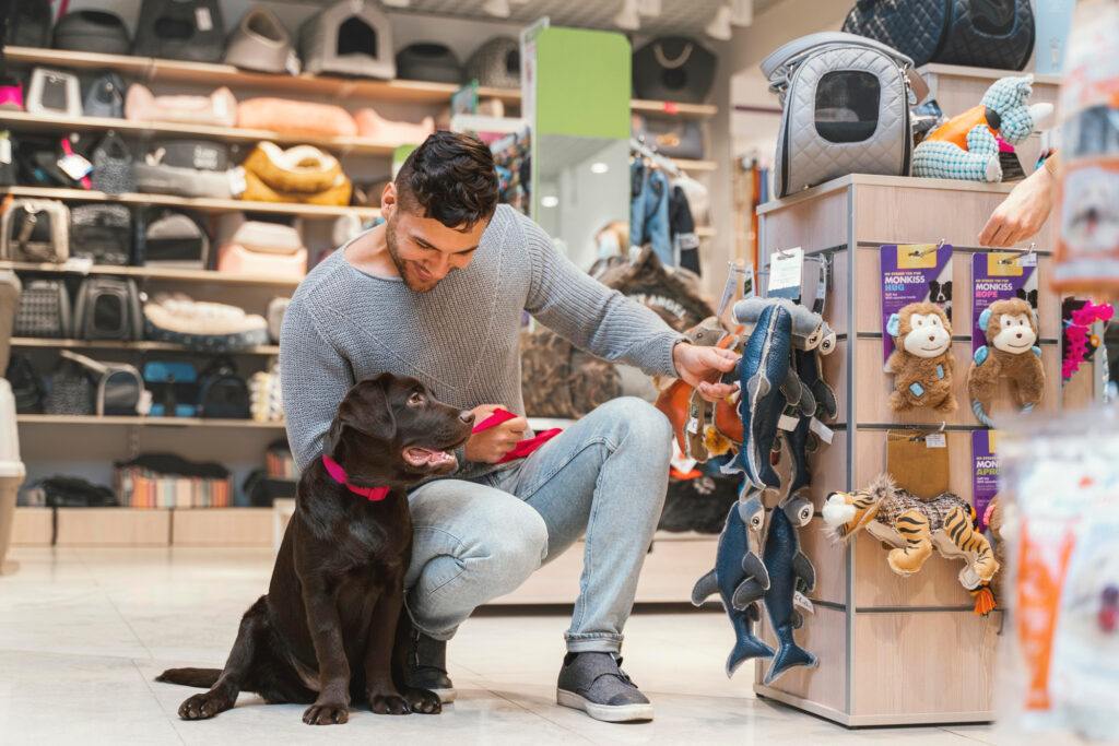Foto de um homem mostrando produtos para um cachorro em um pet shop
